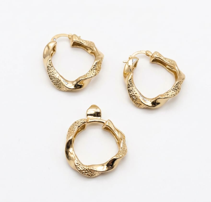 Three gold hoop earrings set on a white background