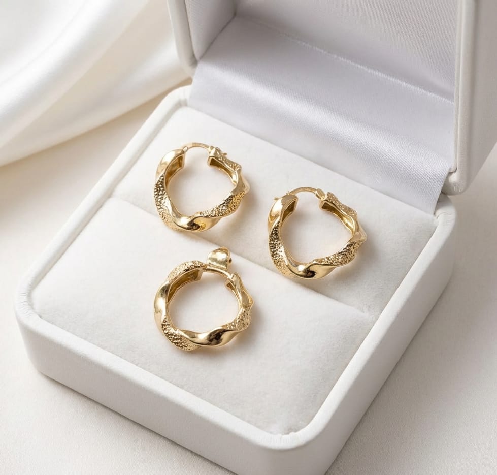 Gold hoop earrings in a white jewelry box on a light background