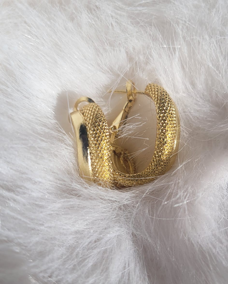 Chunky Huggie hoop earrings on a white fluffy background.