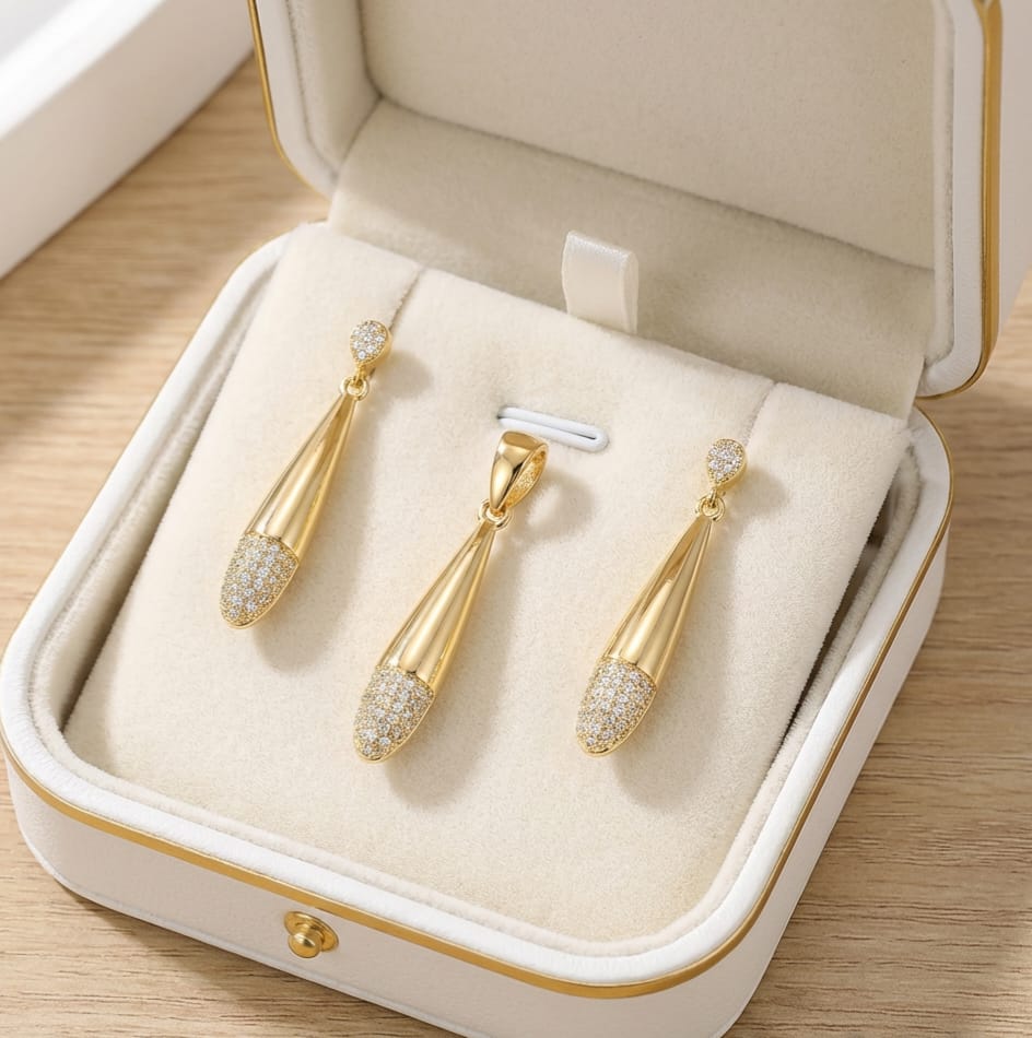 Gold earrings with clear stones in a jewelry box on a wooden surface