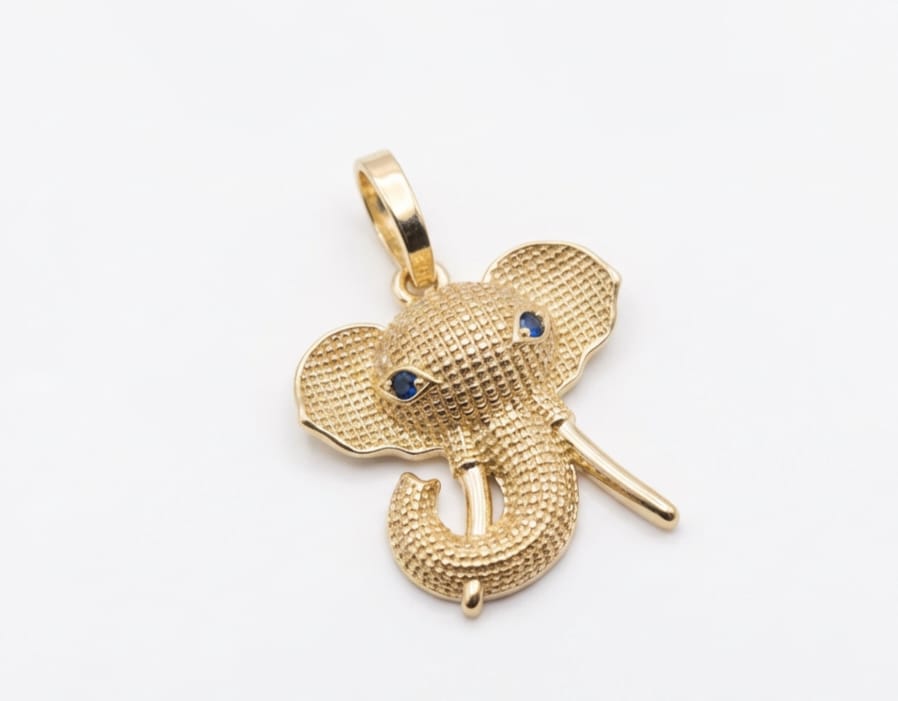 Gold elephant pendant with blue gemstones on a white background