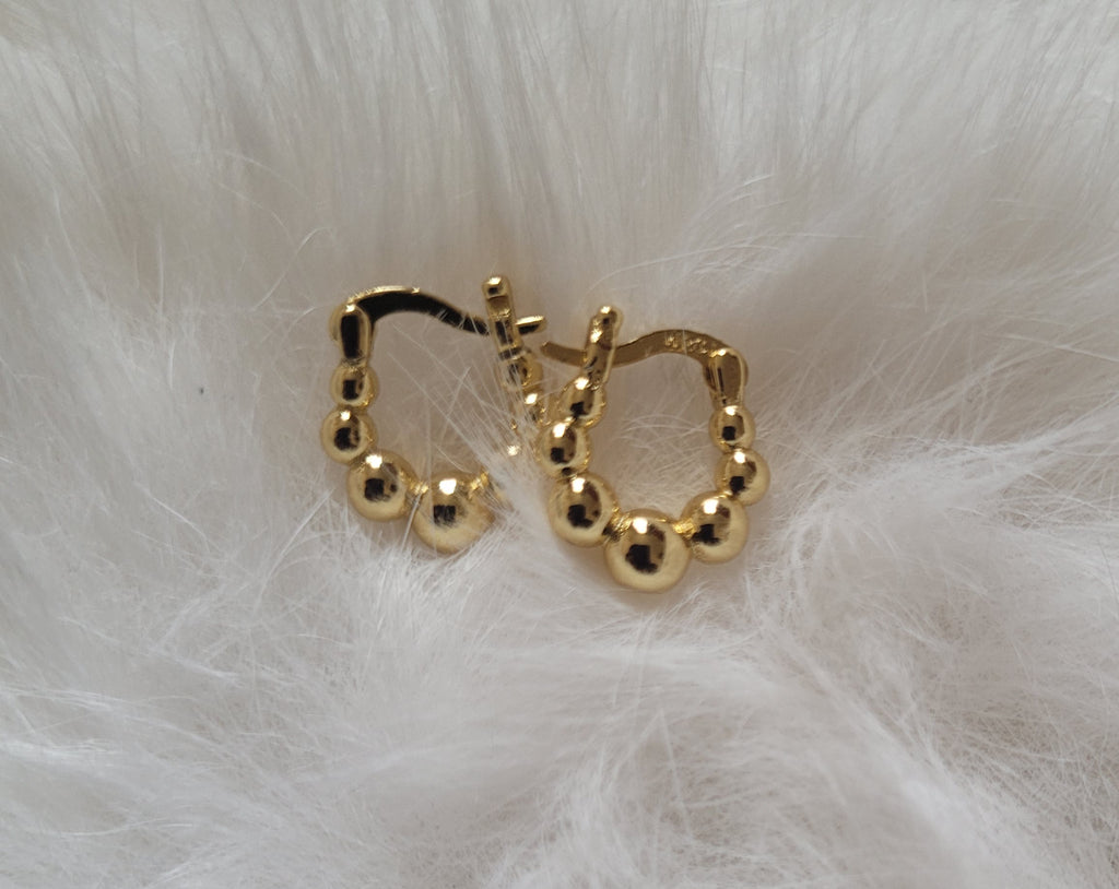 Gold-plated hoop earrings on a white fur background