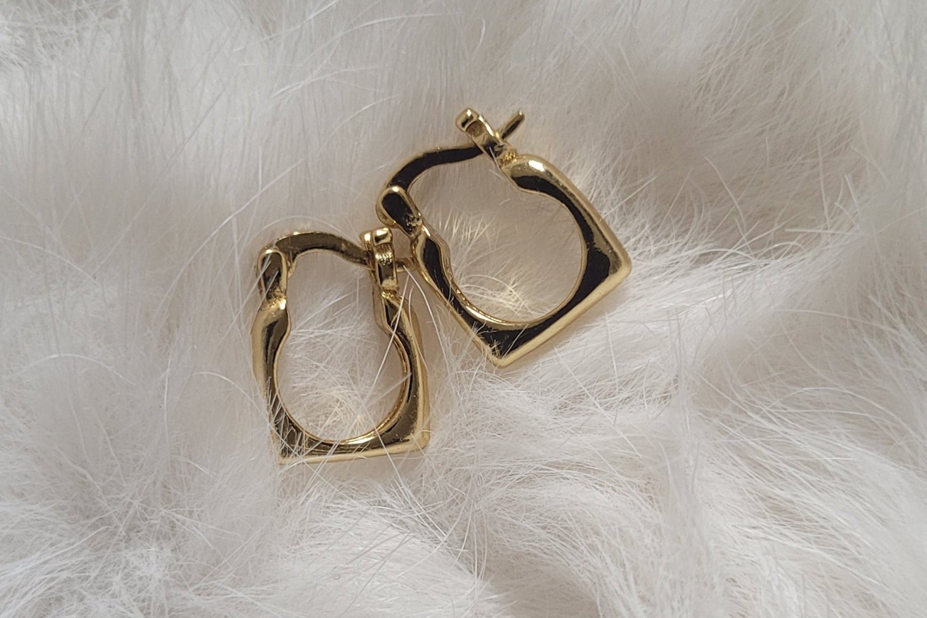 Gold hoop earrings on a white fur surface