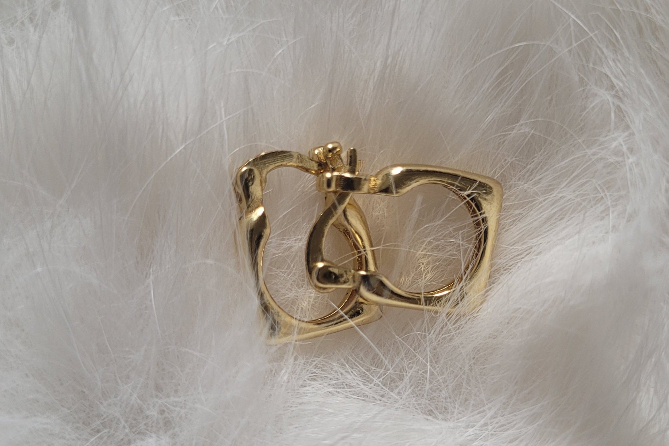 Gold-plated earrings on a white fur background.