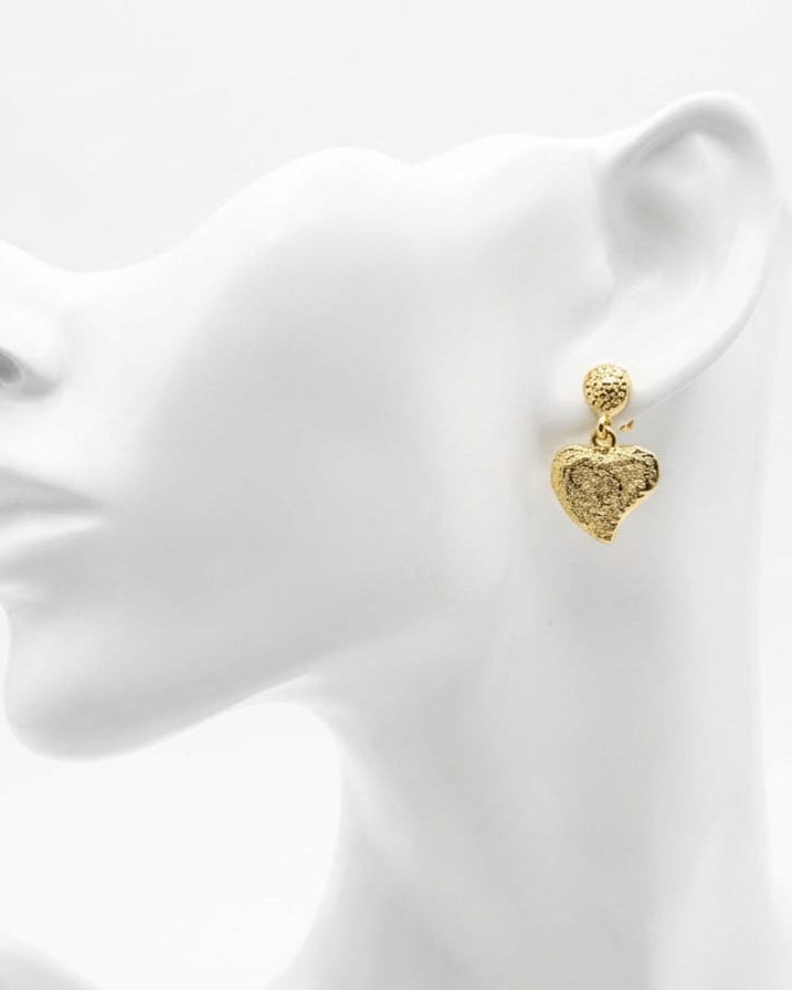 Gold heart-shaped earring on a white mannequin head