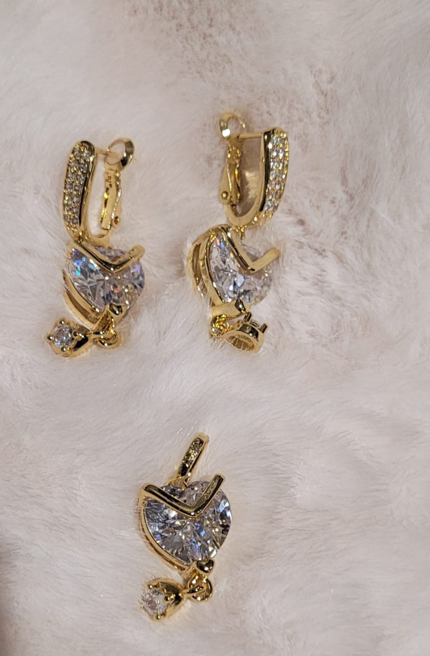 Gold heart-shaped earrings with clear stones on a light background