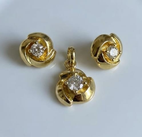 Gold jewelry set with a pendant and two earrings on a light gray background