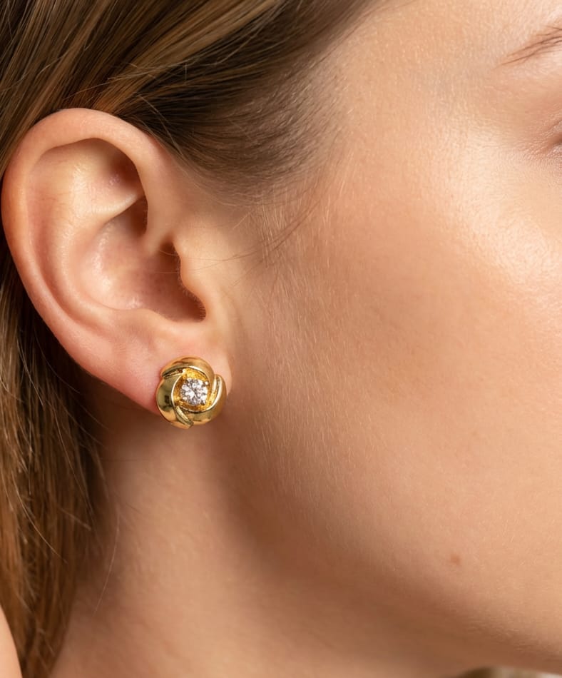 Gold earring with a central fancy stone worn by a person.