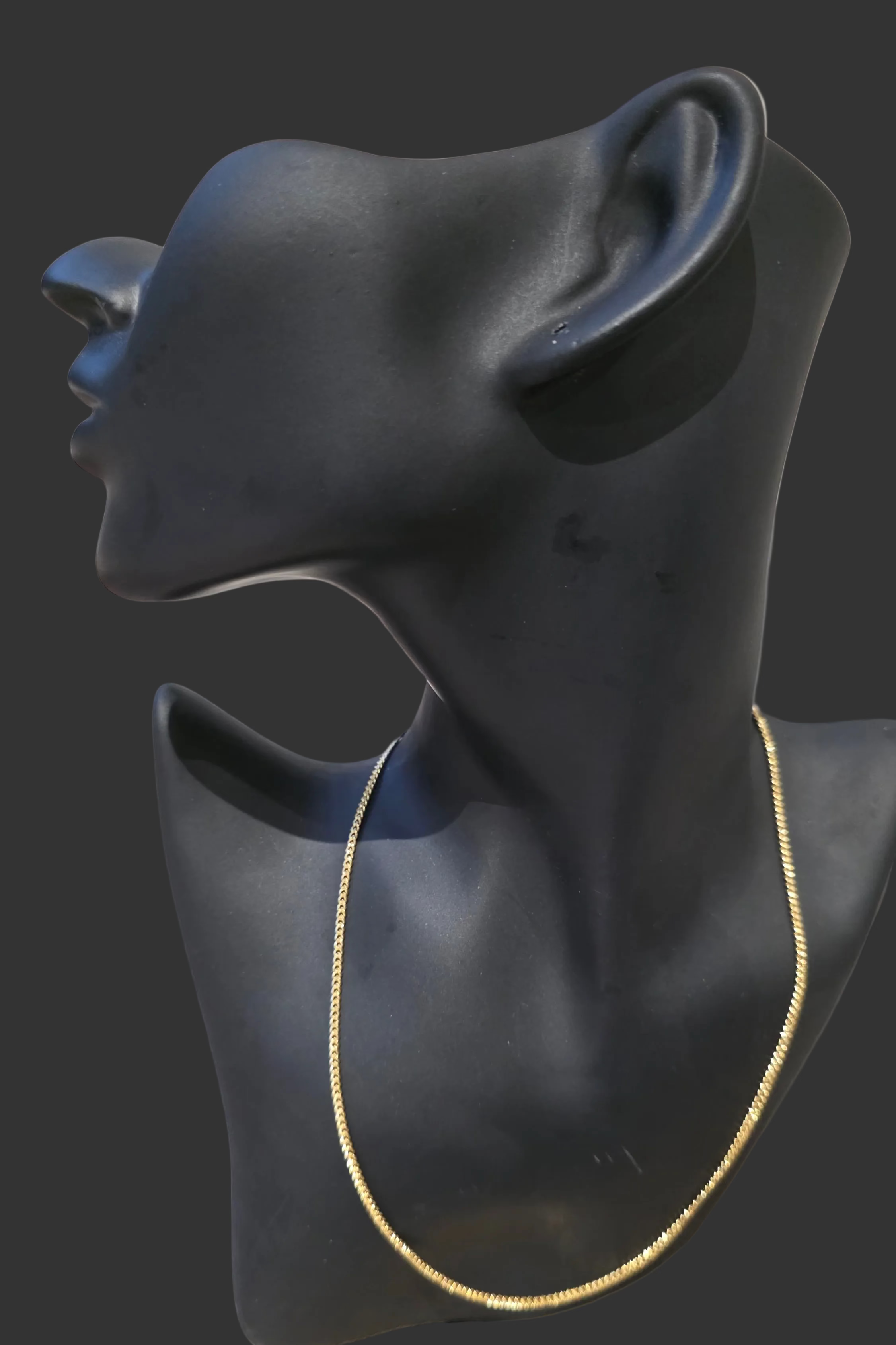 Black mannequin neck and head on a neutral background.