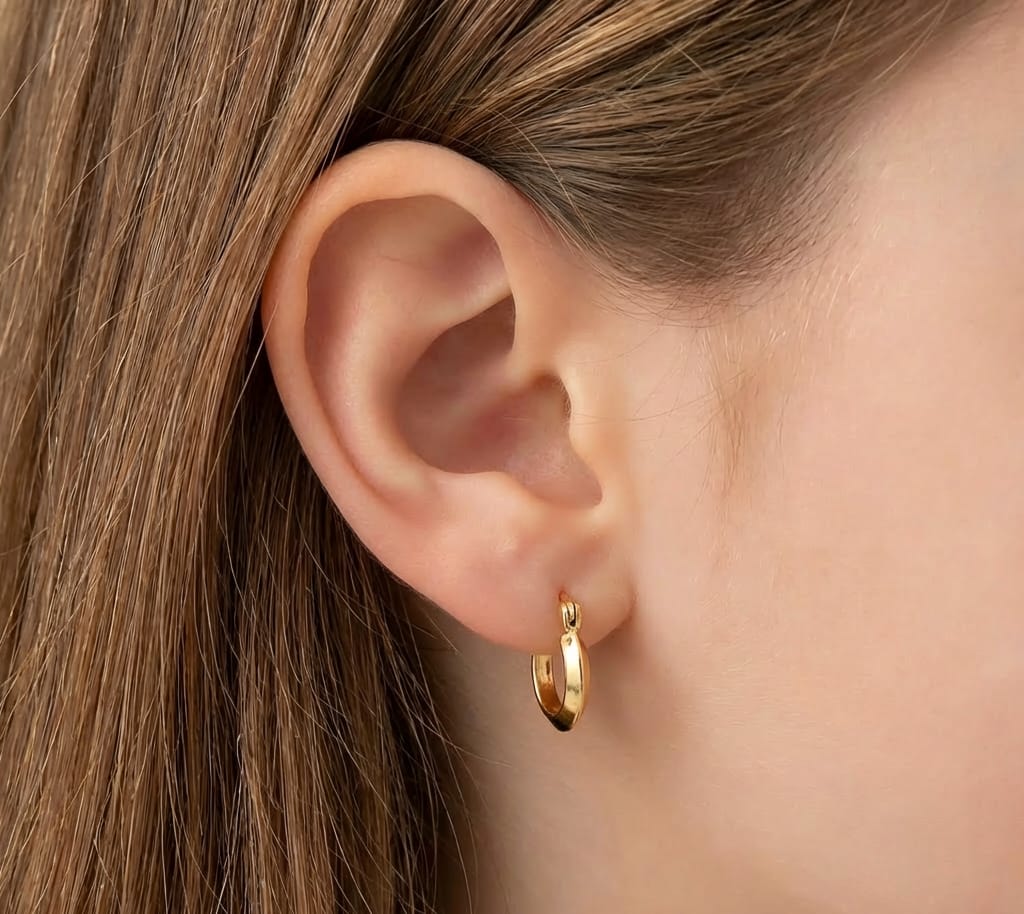 Gold hoop earring worn by a person with brown hair.